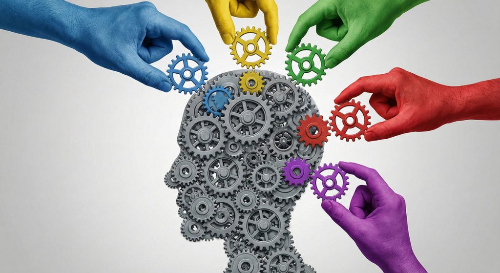Five colored hands place gears into a human head silhouette made of gears, symbolizing collaboration and diverse ideas.